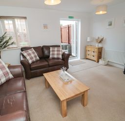 A living room with two brown leather sofas and a wooden coffee table at Brucap Cottage in Beadnell
