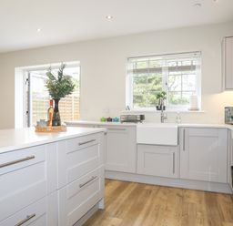 A kitchen with white cabinets a wooden floor a window above the sink and a kitchen island at Iscoed in Llangefni