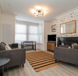 A living room with two gray sofas a striped rug a television and a small table at 11a Manning Road in Felixstowe Suffolk