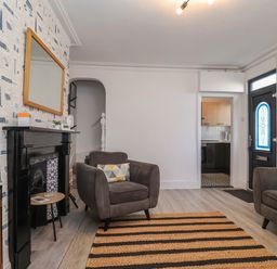 A living room with two armchairs a striped rug and a black fireplace at 11a Manning Road Felixstowe Suffolk