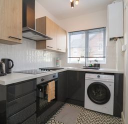 A kitchen with black and wooden cabinets a stove oven washing machine toaster and kettle at 11a Manning Road Felixstowe Suffolk