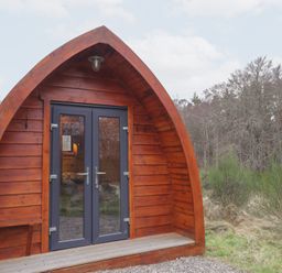 An outdoor view of a wooden pod entrance at Pod 1