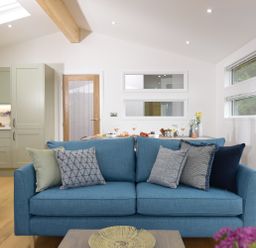 A living room with a blue sofa and cushions next to a kitchen and dining area at 4 Valley View in Lanreath