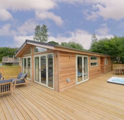 A wooden deck with outdoor seating and a hot tub attached to a wooden cabin at 4 Valley View in Lanreath