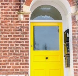 A yellow front door with frosted glass in a brick wall with mailboxes on the right at Flat 3 in Cromer
