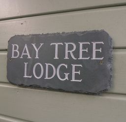 A sign on a wall with the text Bay Tree Lodge at Bay Tree Lodge in Cartmel