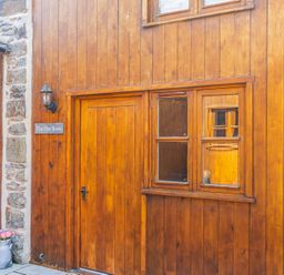An exterior view of The Hay Store with a wooden door and window in Corwen