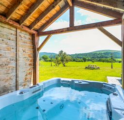 A hot tub under a wooden structure in an outdoor area at The Barn in Corwen