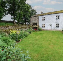 A garden with a house and stone wall at The LA'AL Cragg in Kirkby Stephen
