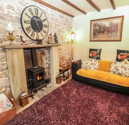 A living room with a sofa and clock on the wall at The LA'AL Cragg in Kirkby Stephen