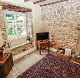 A living room with a television and stone wall at The LA'AL Cragg Kirkby Stephen
