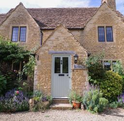 A house with a front door and flowers in the garden at The Old Hall Westonbit Nr Tetbury