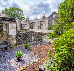 A garden with a table and chairs and plants at The Wonky Burrow in Bowness-On-Windermere