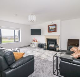 A living room with black leather sofas a fireplace and a wall-mounted television at Old Field House Slade near Fethard-On-Sea County Wexford