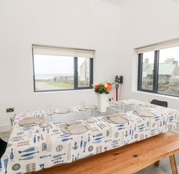 A dining room with a table set for meals and windows showing building exteriors at Old Field House in Slade near Fethard-On-Sea County Wexford