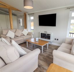 A living room with two beige sofas a wooden coffee table and a wall mounted television at 40 Delamere Point in Delamere