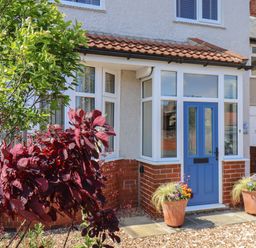 The front entrance of a house with a blue door and two potted plants on either side at North Bay Cottage in Bridlington