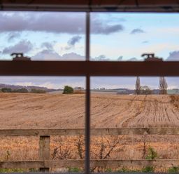 A view of fields and a wooden fence through a window at Robins Nest in Pocklington