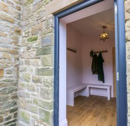 A hallway with wooden floor benches coat hooks and hanging coats at The Coach House in Great Whittington near Corbridge