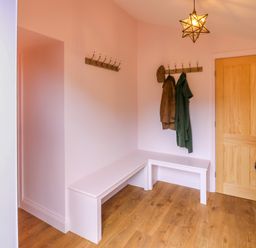 An entryway with wooden floor a wooden door white bench coat hooks with coats and a star-shaped light at The Coach House Great Whittington near Corbridge