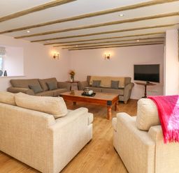 A living room with beige sofas a wooden coffee table a television and wooden ceiling beams at The Coach House in Great Whittington near Corbridge