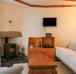 A living room with a wood stove and wooden furniture at Aunt Dora's in Port Isaac