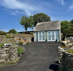 A house with flower pots and stone walls near a pathway at Tower Cottage Near Pembroke