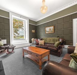 A living room with leather sofas a wooden coffee table and a window with a view at 8 Corkickle in Whitehaven