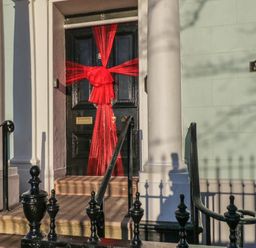 A black front door with a large red bow between two white columns at Floraville 8 Corkickle in Whitehaven
