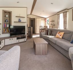 A living room with a grey sofa and cushions a wooden coffee table a television and dining table at 7 The Oaks Long Preston near Hellifield