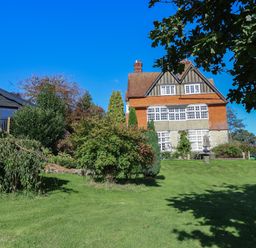 A large house with multiple windows and a red tiled roof surrounded by trees and grass at Sir George Baker Cabin in Uplyme