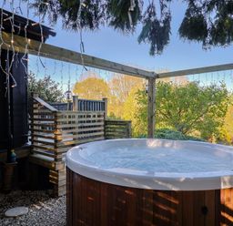 A hot tub on a wooden deck with trees in the background at Sir George Baker Cabin in Uplyme