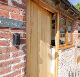 An entrance with a wooden door and sign at The Cow Shed in Bromyard