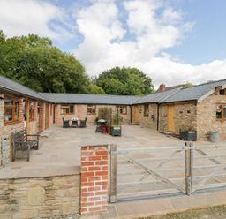 An outdoor area with a stone patio and table at The Cow Shed in Bromyard