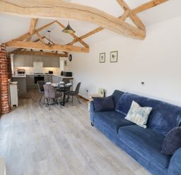 A living room with a sofa and dining area at The Cow Shed in Bromyard