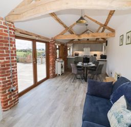 A living room with a sofa and dining area at The Cow Shed in Bromyard