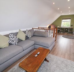 A living room with a grey sofa, wooden coffee table, bookshelf, and a window at Shore Road in Culdaff County Donegal