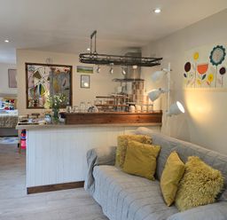 A living room with a sofa and kitchen area at Ty Barddu, Cwmorgan near Newcastle Emlyn