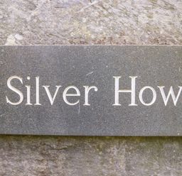 A stone nameplate engraved with Silver How mounted on a rough stone wall
