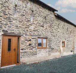 An exterior view of a stone building with wooden door and windows at Godre'r Gyrn, Plas Moelfre Hall Barns, Oswestry