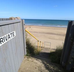 Stone steps with yellow railing leading to a sandy beach and ocean beyond at Beach Haven in Happisburgh East Anglia