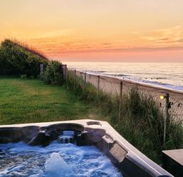 A hot tub near the ocean with a sunset view at Beach Haven Happisburgh, East Anglia