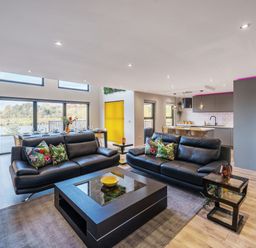 A living room with black leather sofas and a coffee table next to an open kitchen at Micklemore Lakes and Lodges in North Thoresby