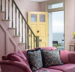 A living room with a staircase and yellow door at Astondene, East Cliff, Southwold