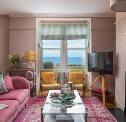 A living room with a sofa, TV and coffee table at Astondene, East Cliff, Southwold