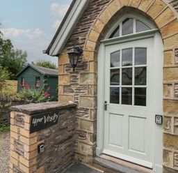 A stone entrance with a pale green arched door and a sign reading Upper Vestry in Llangrannog