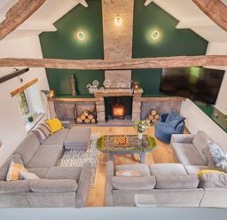 A living room with grey sofas a wood burning stove and a TV mounted on the wall at The Waterfall Retreat in Orton