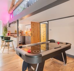 A game room with an air hockey table a bar area with stools and bottles and a wooden door at The Waterfall Retreat in Orton