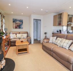 A living room with two leather sofas a wooden coffee table and a wood burning stove at Eden Lodge in Castlewigg near Whithorn
