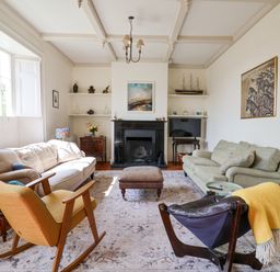 A living room with two sofas a yellow rocking chair a black leather chair a fireplace and a television at Charmouth Lodge in Charmouth